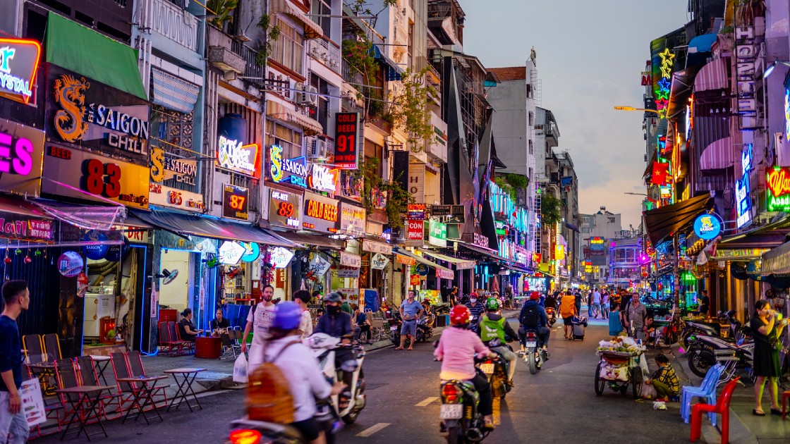 Motorbikes on a neon-lit street in Ho Chi Minh City at night
