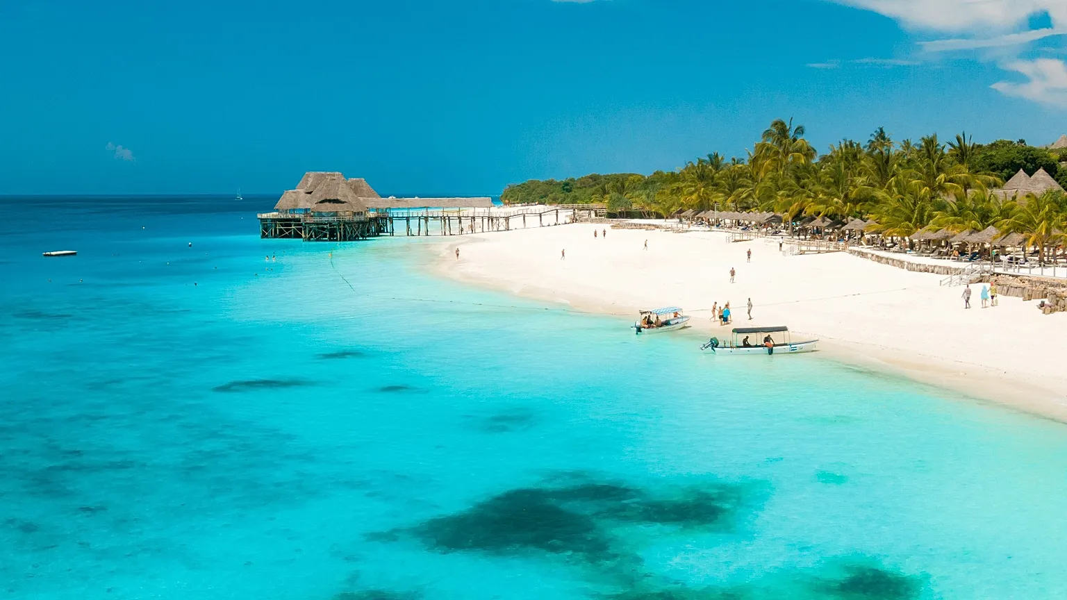 White sand beach and turquoise water on Zanzibar with a thatched pier restaurant
